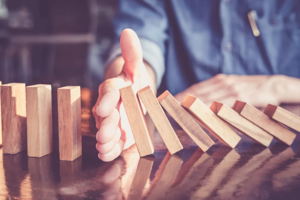 A hand blocking dominos from falling.