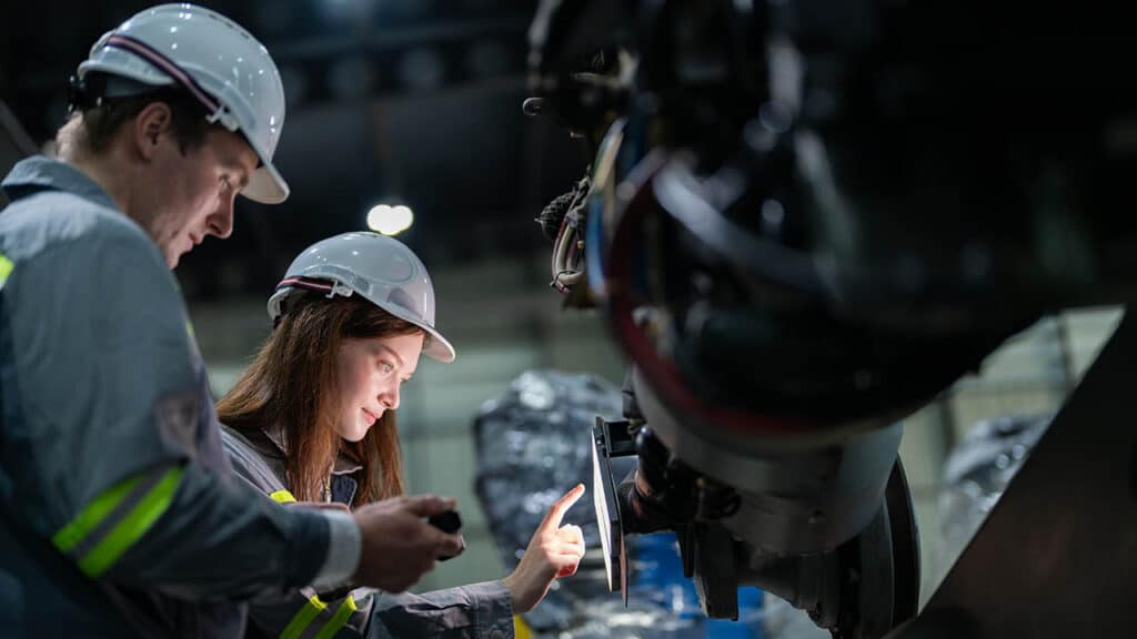 Engineers verifying a CAPA corrective action fix on machinery in a manufacturing facility