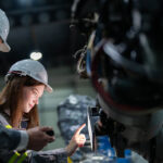 Engineers verifying a CAPA corrective action fix on machinery in a manufacturing facility