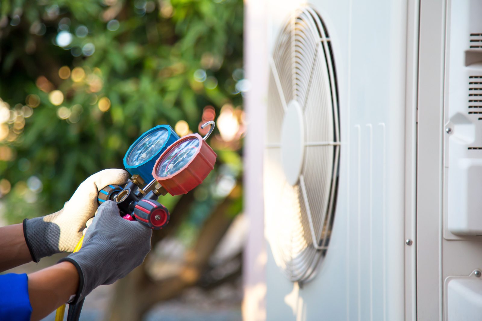 HVAC outdoor unit inspection HVAC technician inspecting an outdoor compressor unit and checking refrigerant with manifold gauges.